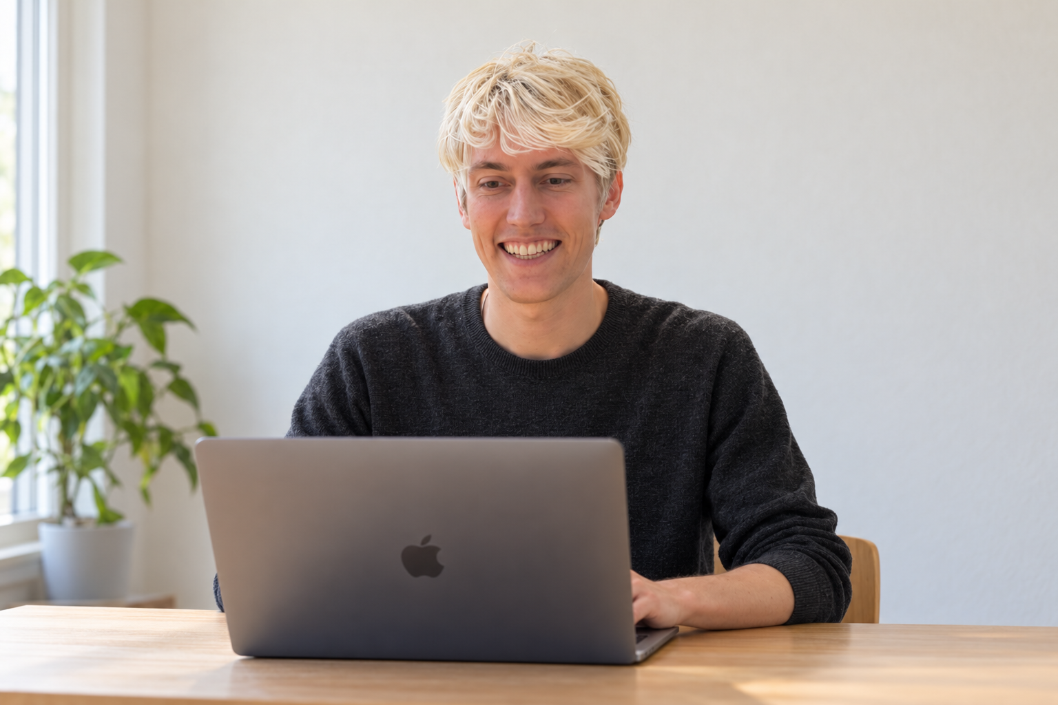 Maximilian Messler sitzt lächelnd vor seinem Laptop für ein persönliches Videogespräch.